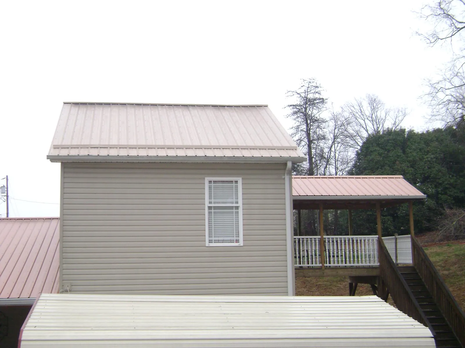 Tan metal roofs on a two story addition and attached porch, from a Roof Replacement job in Coronado