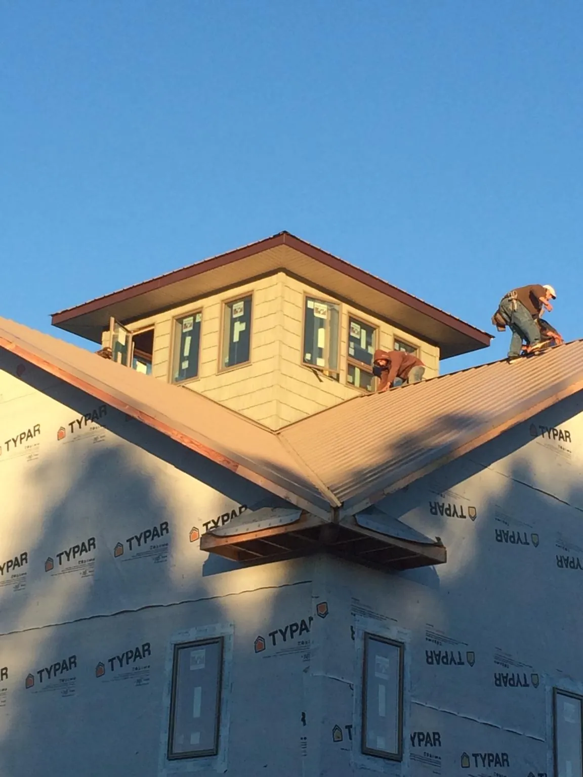 Roofers working around a rooftop cupola on a new metal roof at sunset — Roof Waterproofing in Coronado by Roofing Brothers
